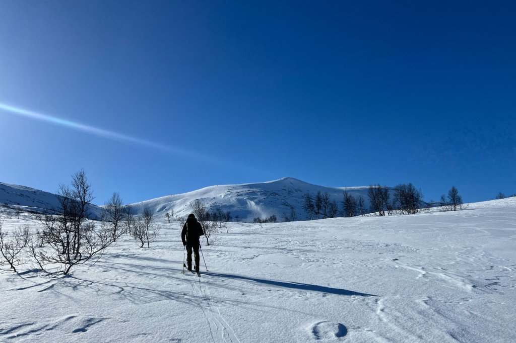 Person som går innover fjellet på ski. Foto.